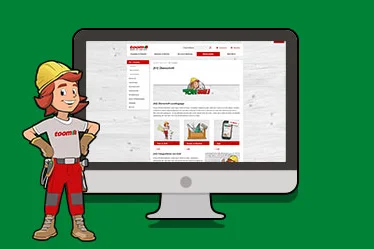 Comic-Figur Tom steht neben der toom.de Website auf Computerbildschirm